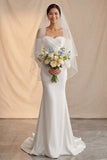 Vestido de novia bohemio con cola sirena en marfil descubierto y mangas de encaje