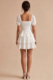 Una línea de vestido mini blanco con volantes y escote cuadrado con mangas abullonadas
